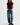 A woman wearing high rise barrel jeans in medium wash with a short sleeve maroon tee and black loafers on a white background.