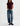 A woman wearing high rise barrel jeans in medium wash with a short sleeve maroon tee and black loafers on a white background.