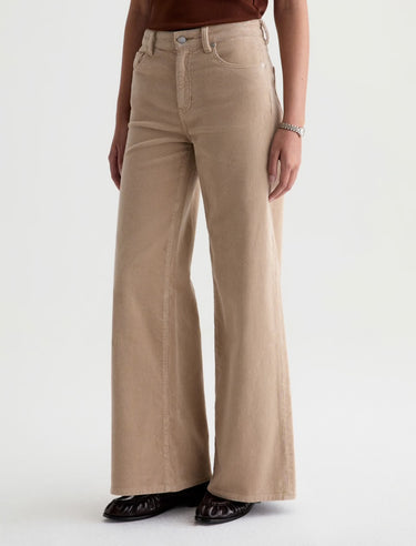 A woman wearing wide leg tan corduroy pants with a relaxed silhouette on a white background