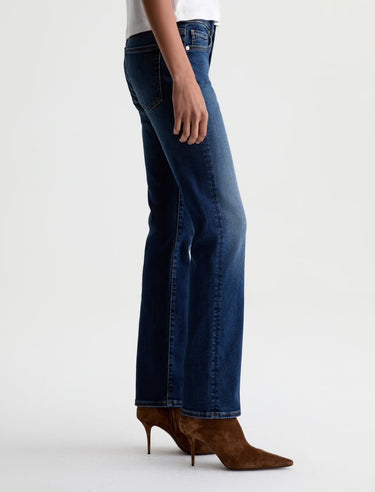 Person wearing blue jeans and brown boots on a white background