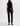 A woman wearing low rise straight dark blue jeans and black heels on a white background.