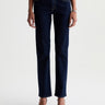 A woman wearing low rise straight dark blue jeans and black heels on a white background.