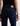 A woman facing backwards wearing low rise straight dark blue jeans and black heels on a white background.