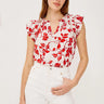 Woman wearing a red floral top and white pants on a white background