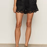 Women wearing black linen shorts with scalloped edges on a neutral background 