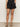 Women wearing black linen shorts with scalloped edges on a neutral background 