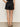 A back view of a women wearing black linen shorts with scalloped edges on a neutral background 
