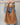 A woman holding a slouchy brown suede hobo shoulder bag with a single strap on a neutral background 