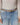 Person wearing light blue jeans with a patterned belt and beige sweater.