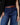 Person wearing blue jeans with a brown belt on a neutral background