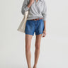 Person wearing a light gray sweater, blue denim shorts, and brown shoes on a white background