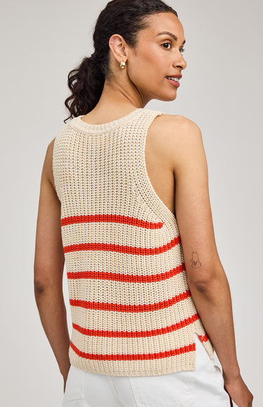 Woman wearing a sleeveless knitted top with red stripes on a plain background