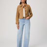 Woman wearing a tan jacket and light blue jeans on a white background