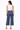 a woman wearing a white tank and dark cropped denim jeans on a white background