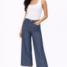 A woman wearing a white thank and dark cropped denim jeans