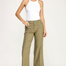 Woman wearing a white tank top and green pants on a white background