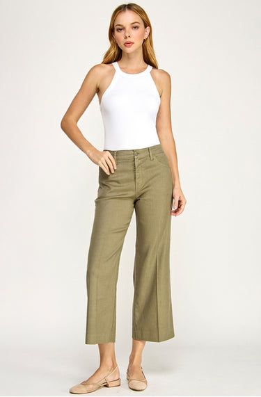 Woman wearing a white tank top and green pants on a white background