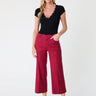 Woman wearing a black top and red cropped wide leg pants on a white background