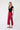 Woman wearing a black top and wide leg cropped red pants on a white background