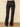Black wide-leg flare pants shown from the back on a model, paired with black high heels, set against a beige wall and a textured tan rug.