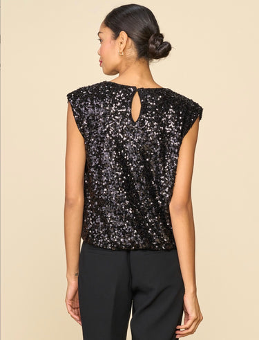 A woman wearing a sleeveless sequin tank with keyhole detail in the back