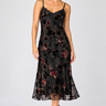 a woman wearing a black dress with lace along the neckline and colorful floral velvet detailing.