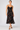 a woman wearing a black dress with lace along the neckline and colorful floral velvet detailing.