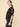 A woman wearing a velvet floral mesh blouse and black jeans on a neutral background.