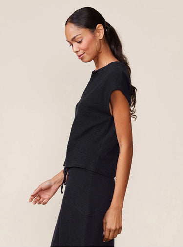 Woman wearing a black outfit against a beige background