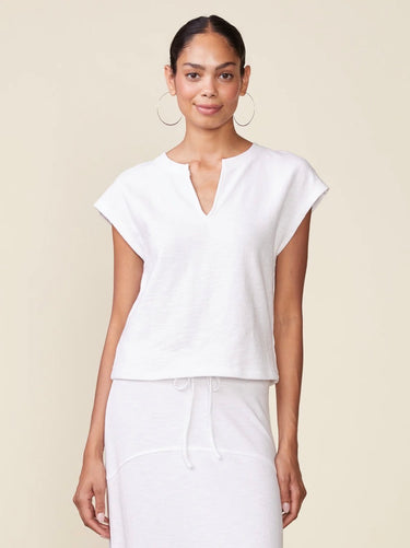 Woman wearing a white blouse and pants against a beige background