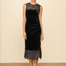 A woman wearing a midi dress with high lace neckline, a velvet body and a lace trim n a neutral background