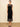 A woman wearing a midi dress with high lace neckline, a velvet body and a lace trim n a neutral background