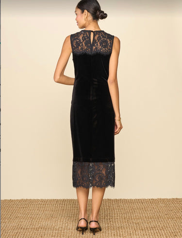 A woman wearing a lace and velvet midi dress on a neutral background