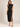 a woman wearing a black lace mock neck  sleeveless dress with a front slit on a white background