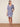 Woman wearing a blue floral dress standing on a textured surface with a neutral background