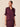 A woman modeling a dark plum satin blouse with short ruffled sleeves and a split V-neckline, paired with a matching satin skirt against a solid beige background.