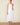 Woman wearing a white halter neck dress on a beige background