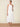 Woman wearing a white halter neck dress on a beige background