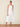 Woman wearing a white halter neck dress on a beige background