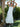 Woman in a white dress standing outdoors with greenery around