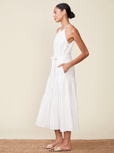 Woman wearing a white dress standing against a beige background