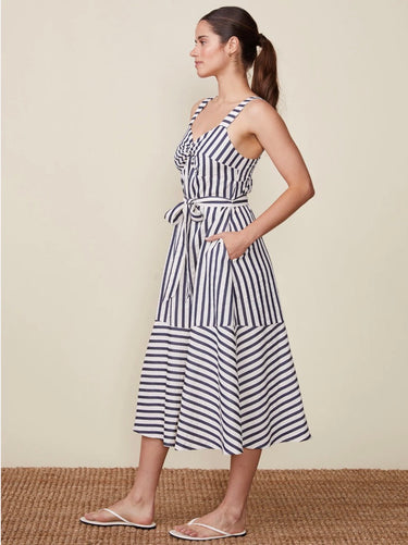 Woman wearing a black and white striped dress against a beige background
