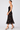 a woman wearing a black dress with lace along the neckline and colorful floral velvet detailing.