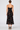 a woman wearing a black dress with lace along the neckline and colorful floral velvet detailing.