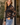 a woman wearing a lace sheer blouse with a bralette and blue jeans in outside a house setting.