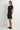 Woman wearing a black dress standing against a white background