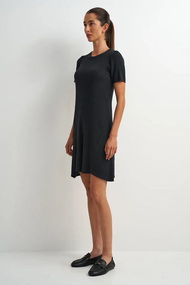 Woman wearing a black dress standing against a white background
