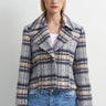 A woman wearing a blue plaid flannel jacket and blue jeans on a white background.