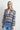 A woman wearing a blue plaid flannel jacket and blue jeans on a white background.