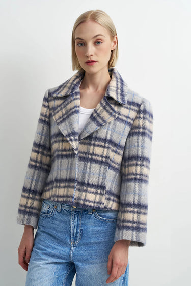 A woman wearing a blue plaid flannel jacket and blue jeans on a white background.